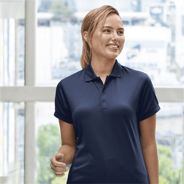**Alt Text:** Smiling woman wearing navy custom polo shirt – personalised uniform with free printed logo included, ideal for workwear and team branding.