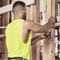 Male tradie wearing hi-vis yellow safety singlet on construction site – lightweight custom singlet with free printed logo included.