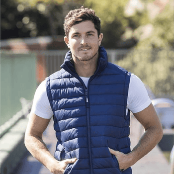**Alt Text:** Man wearing royal blue custom puffer vest outdoors – personalised corporate vest with free logo included, ideal for staff uniforms and business branding.