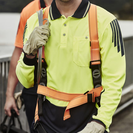 A worker wears a neon yellow and dark blue long-sleeve polo with black shoulder stripes and a safety harness, holding a wire cable.