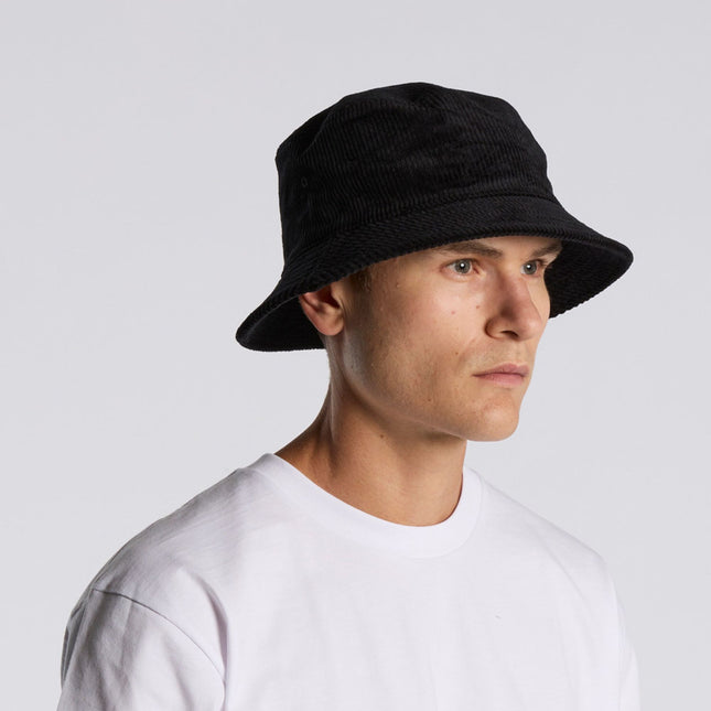 A person in an AS Colour Cord Bucket Hat and plain white tee looks to the side against a light gray background—ideal inspiration for custom logo hats or personalised workwear with the AS Colour Cord Bucket Hat.