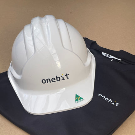 White hard hat with 'onebit' branding on a black surface