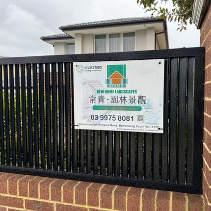 Real estate sign on a black metal fence with a house in the background