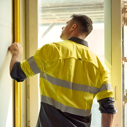 A person stands facing away, wearing a neon yellow and dark gray long-sleeve work shirt. It has gray reflective stripes on the torso and arms.