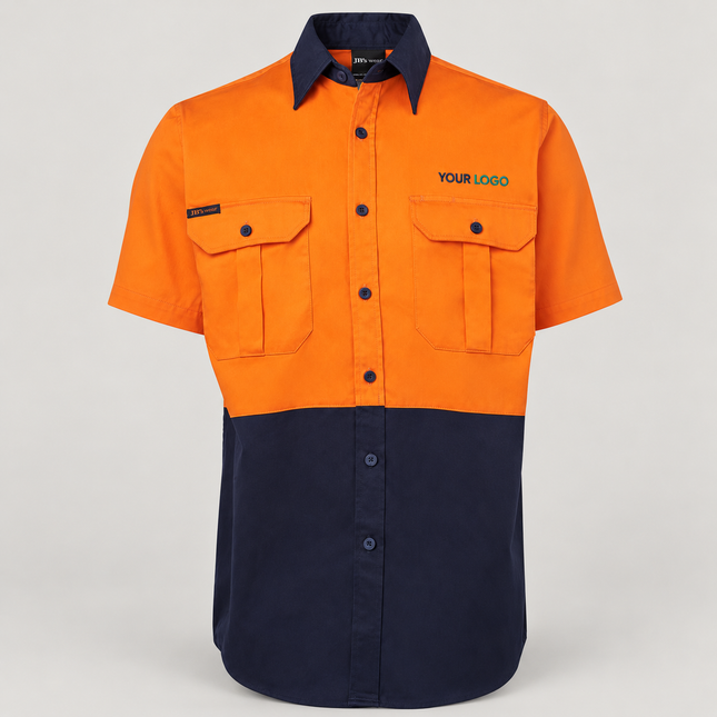 Illustrative front-view branding mock-up of JB's Wear 6HWS Orange/Navy shirt with small navy-and-teal YOUR LOGO embroidery above the wearer-left chest pocket on a warm grey background.