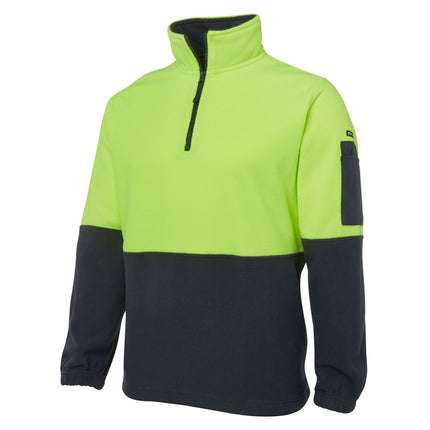 A close-up of a two-tone fleece pullover. The top is neon yellow, and the bottom and sleeves are dark blue. It has a high collar with a half zipper and a small black pocket on the left sleeve.