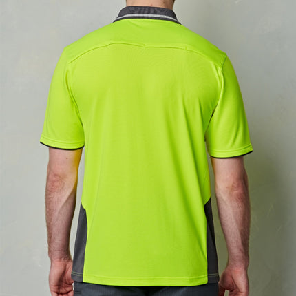 A rear view of a man wearing a neon yellow polo shirt with gray side panels and black piping.