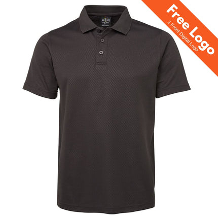 A JB's Wear Podium Cotton Back Yardage Polo in plain black with short sleeves, collar, and three buttons is shown on a white background. An orange banner at the top right reads "Free Logo and 1 Front Digital Logo.