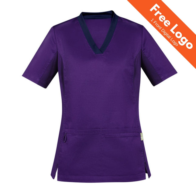 The Biz Care Womens Riley Stretch Scrub Top features short sleeves, stretch purple fabric, a dark V-neck collar, and two front pockets. An orange banner in the top right corner says “Free Logo, 1 Front Digital Logo.”.
