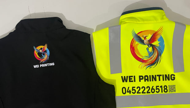 Black jacket with a colorful logo and text on the back, next to a yellow safety vest with a similar design.