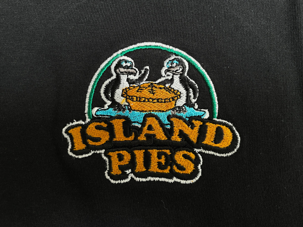 Island Pies logo embroidered in coloured thread on black fabric, showing the finished stitch texture.
